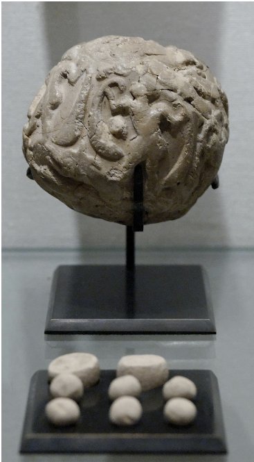 A round clay bulla on a stand, with eight small clay tokens laid out on a tray below it.